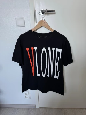VLONE t-shirt med tryck - Säljer en svart t-shirt från VLONE med stort vitt och orange tryck på framsidan och en stor orange V på ryggen. Klassisk rund hals och korta ärmar. Perfekt för dig som gillar streetwear och vill sticka ut med en ikonisk design. Used but still in good condtion. Size M.