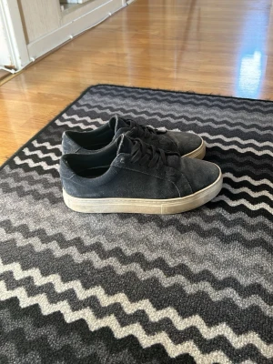 Svarta låga sneakers i canvas - Säljer ett par svarta sneakers i canvas med vit sula och klassisk låg profil. Skorna är större i storleken.