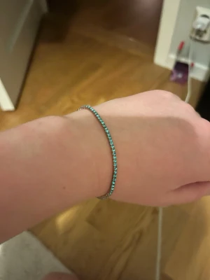 Tunt armband med turkosa pärlor - Snyggt och minimalistiskt armband med små turkosa pärlor runt hela bandet. Armbandet är tunt och flexibelt, perfekt för dig som gillar diskreta men färgglada accessoarer. Ingen synlig logga eller märke.