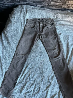 Beige slim fit jeans från Replay - Säljer ett par beige slim fit jeans från Replay, modell Anbass. Jeansen har slitningar vid knäna, klassisk femficksdesign och är tillverkade i ett mjukt bomullsmaterial med lite stretch. Perfekta för en avslappnad och trendig look.