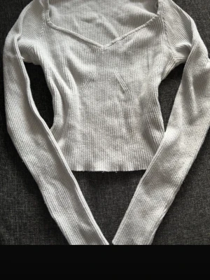 Ribbad vit/turkos topp – figurnära & trendig - Superfin ribbad topp som sitter så snyggt på kroppen och ger en clean, stilren look ✨ Perfekt både till jeans, kjol eller mjukis för en mer avslappnad outfit.  Detta får du: – Ribbat material som formar sig efter kroppen – Långärmad modell – Smickrande v-ringning – Croppad längd  Varför du vill ha den: En riktig basic med det lilla extra – enkel att matcha men ändå trendig. Passar både till vardag och lite mer uppklätt.  Skick: Knappt använd Mycket fint skick  Storlek & märke: Storlek S Shein 