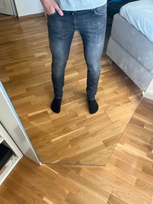 Mörkgrå slim fit jeans - Säljer ett par mörkgrå slim fit jeans med klassisk femficksdesign och snygg tvätt. Jeansen har smal passform och normal midja, perfekta till en avslappnad stil. Materialet är mjukt denim som sitter skönt hela dagen. Skickas snabbt och hör av er vid minsta funderingarna!!