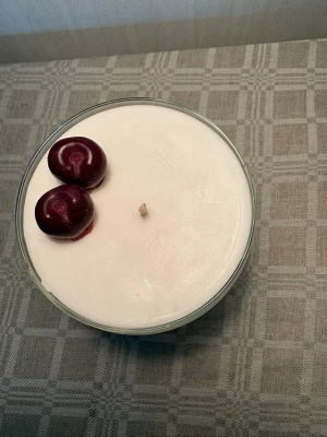 Doftljus cherry bomb - Unikt doftljus i ett genomskinligt glas på fot, dekorerat med en körsbärsformad detalj på toppen. Ljuset har en vit bas med ett rött lager i mitten som ger en snygg effekt. Perfekt som dekoration eller present.