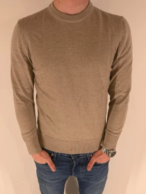 Beige finstickad tröja från Zara - Riktigt stilren och snygg beige finstickad tröja med rund hals. Tröjan har ribbade muddar vid ärmslut och nederkant, vilket ger en snygg passform. Säljer pga att den är något tajt. Jag är 173cm och väger 62kg. 