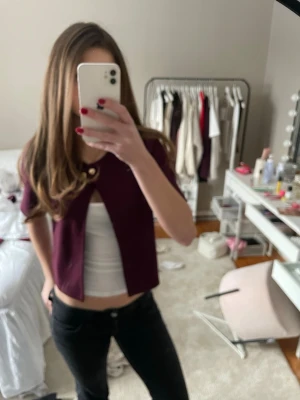 Vinröd kortärmad kofta från Gina Tricot - Kortärmad vinröd kofta från Gina Tricot med guldfärgad knapp framtill. Tillverkad i en mjuk blandning av viskos, polyester och elastan för en bekväm och stretchig passform. Perfekt att styla över linne eller klänning. 