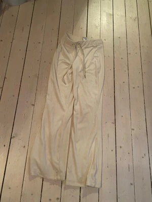 Beige vida mjukisbyxor  - Säljer ett par beige mjukisbyxor med breda ben och dragsko i midjan. Byxorna har en avslappnad passform och är perfekta för chill dagar. Tillverkade i mjukt material som känns skönt mot huden.