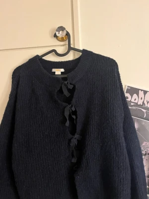 Marin blå stickad kofta med rosetter - Mysig svart stickad kofta från Gina Tricot. Koftan har rund halsringning och lång ärm, perfekt för lager på lager och en trendig look.