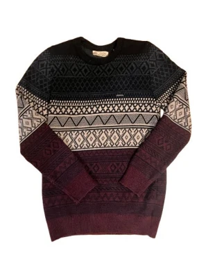 Mönstrad stickad tröja i vinrött och svart - Stickad tröja med snyggt geometriskt mönster i svart, vinrött och beige. Tröjan har rund halsringning och långa ärmar. Perfekt för kalla dagar och ger en cool retrovibe till din outfit. Materialet känns mjukt och bekvämt.