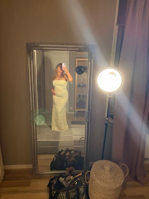 Lång offshoulder klänning i spets - Elegant långklänning i ljus spets med offshoulder-design och figurnära passform. Klänningen har en vacker omlott-effekt över bysten och är helt ärmlös, vilket ger en stilren och modern look. Man kan även välja på att ha banden över armarna eller inte beroende på vad man tycker är snyggast. Perfekt för speciella tillfällen!💕