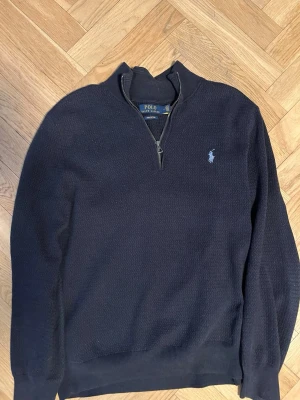 Mörkblå halvzip från Polo Ralph Lauren - Mörkblå tröja från Polo Ralph Lauren med halvzip och diskret broderad logga på bröstet. Tillverkad i bomull med strukturerad yta, ribbade muddar och hög krage. Perfekt för en stilren och avslappnad look. 100% äkta och nypriset var 1799 kr. Storlek M, passar även S. Absolut inga skador på tröjan. Pris kan diskuteras 