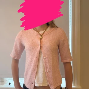 Ljusrosa kofta med pärlknappar från Gina Tricot  - Söt ljusrosa kofta i mjukt stickat material med trekvartsärm och rund hals. Koftan har fina pärlknappar framtill. 