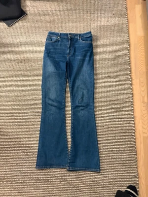 Blå bootcut jeans !! 💙💙💙💙 - Säljer ett par klassiska blå bootcut jeans med hög midja och utsvängda ben. Jeansen har fem fickor, bälteshällor och stängs med knapp och dragkedja. Perfekta till sneakers eller boots för en avslappnad look.
