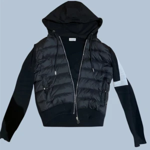 Moncler Cardigan - Moncler cardigan, helt oanvänd. Stilren modell med dunfront och huva. Nypris högt – säljes billigt. Perfekt skick. NFC finns i Moncler-Patchen. 
