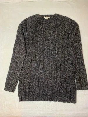 Mörkgrå ribbstickad tröja - Mysig mörkgrå ribbstickad tröja med rund hals och långa ärmar. Tröjan har en klassisk rak passform och är tillverkad i ett mjukt, melerat garn som ger en stilren look. Perfekt för lager på lager under kyliga dagar.