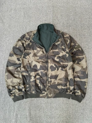 Grön Woolrich Reversible vindjacka storlek S - Grön Woolrich Reversible vindjacka i militärmönster Inga defekter Storlek EU L men sitter som S Hör av er vid frågor!