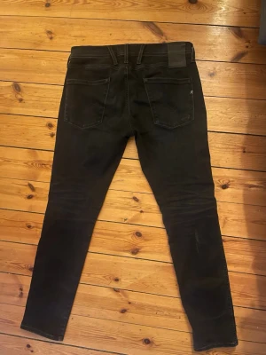 Svarta Replay Hyperflex jeans - Säljer ett par svarta Replay Abbass Hyperflex jeans, Perfekta för dig som gillar stilrena och bekväma jeans. 