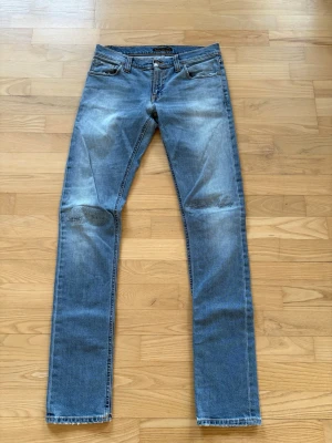 Nudie jeans - Säljer ett par blå jeans från nudie jeans med raka ben och snygga lagningar vid knäna. Jeansen har klassisk femficksmodell, normal midja och ljus tvätt med faded effekt. Perfekta för en avslappnad och trendig look. Priset kan absolut diskuteras för att båda ska bli nöjda!!