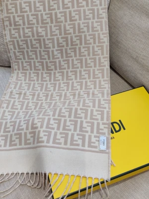 Beige Fendi halsduk med FF-mönster - Verkligen lyxig beige halsduk från Fendi med ikoniskt FF-logomönster i ljusbeige och creme. Halsduken tillverkad i mjukt material ull som känns exklusivt. Ingen kvitto finns, fick som present. Färgen passar inte riktigt min garderob.
