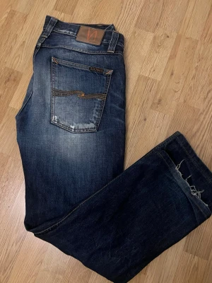  Nudie Jeans easy emil - Snygga mörkblå jeans från Nudie Jeans med klassisk femficksdesign och slitningar. Sällsynt utgående modell easy emil som ger jeansen en rak passform. Modellen är 190 och storleken på jeansen är 34/34. 