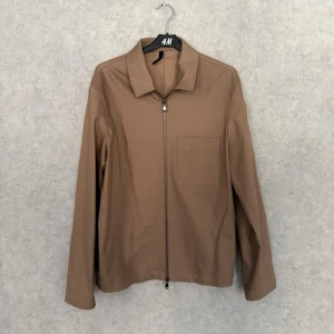 J Lindeberg Zip/Overshirt - Säljer en stilren zip-jacka från J.Lindeberg i en varm brun/beige ton. Minimalistisk design med snygg struktur i tyget och hög kvalitet rakt igenom – exakt den typen av plagg som lyfter en hel outfit utan att ta över. 🔹 Märke: J.Lindeberg 🔹 Storlek: S 🔹 Färg: Brun / beige 🔹 Passform: Rak, modern 🔹 Detaljer: Hel dragkedja, bröstficka, diskret branding 🔹 Skick: Mycket bra