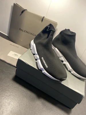 Balenciaga Speed Trainer svarta sneakers - Svarta Balenciaga Speed Trainer sneakers med stickad ovandel i textil och vit chunky sula. Strumpliknande passform och Balenciaga-logga på sidan. Superlätta och flexibla, perfekta för en trendig streetwear-look.