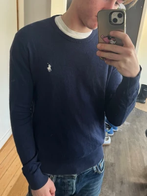 Mörkblå  Kashmir tröja från Ralph Lauren - Snygg mörkblå tröja från Ralph lauren i Kashmir . Tröjan har långa ärmar och ribbade muddar vid ärmslut och nederkant. Perfekt att matcha med jeans för en clean look. Tröjan är i väldigt bra skick, men har ett väldigt litet hål längre ner.