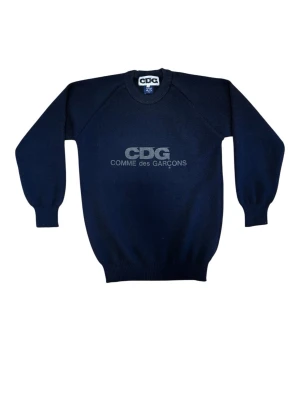 Comme des garçons tröja - Stickad mörkblå tröja från Comme des garçons med logotyp tryck i svart. Mycket fint skick, inga defekter. Mått skrivs nedanför.  Längd: 70 cm Bredd: 50 cm Armlängd: 68 cm obs! Tröjan är rättså töjbar.