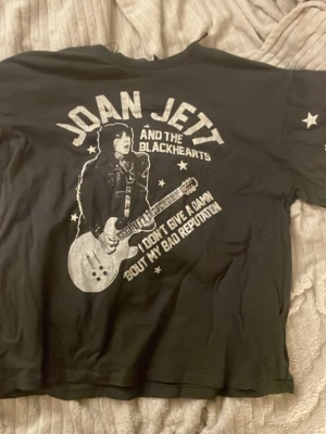 Mörk grå  cool t-shirt med tryck - Cool svart t-shirt med stort Joan Jett and the Blackhearts-tryck på framsidan och vita stjärnor på ärmen. T-shirten har korta ärmar och är gjord i mjuk bomull. Perfekt för dig som gillar rock och vill ha en statement tee.ÄR MER SOM EN S I STORLEK 