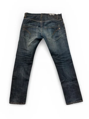 DonDup jeans  - Snygga mörkblå jeans med raka ben och slitningar för en cool look. Jeansen har kontrastsömmar, fem fickor och klassisk knappgylf. Passar perfekt till en avslappnad streetstil och är tillverkade i denim med en skön känsla.