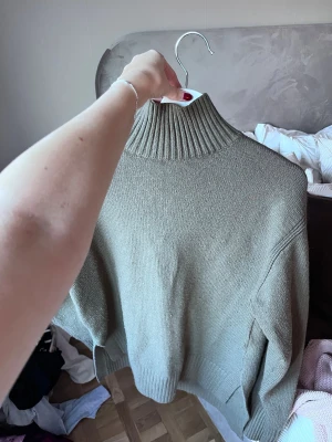 Olivgrön stickad polotröja - Säljer en olivgrön stickad polotröja med hög ribbad krage och långa ärmar.