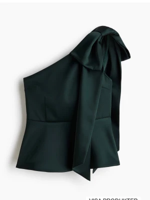Mörkgrön oneshoulder topp med rosett - !!Prislappen är kvar!!Stilren mörkgrön oneshoulder topp i satinliknande material med stor rosett på axeln. Aldrig använd då den var för liten