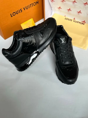 Svarta Louis Vuitton sneakers - Snygga svarta sneakers från Louis Vuitton med klassisk LV-logga på plösen och monogramdetaljer på sidorna. Skorna är tillverkade i läder och har en chunky sula för extra attityd. Perfekta för dig som vill ha en exklusiv och trendig look.