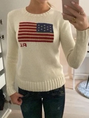 Vit stickad tröja Polo Ralph Lauren - Vit stickad tröja från Polo Ralph Lauren med amerikansk flagga och RL-broderi framtill. Klassisk och tidlös design. Storlek XXS dam, i använt skick men fortfarande fin! Inga fläckar. Nypris 4995:-