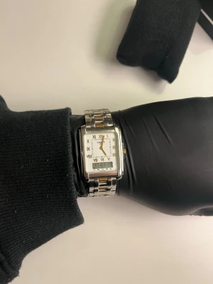 Tissot - Tissot Two Timer D130/230K klocka i super kvalitet, tillverkad i Schweiz. Klockan har blivit verifierad av Vinted och fått certifikat på detta som även det följer med. En riktigt fin klocka som håller sitt värde för den som gillar investeringar. Fungerar lika fint som en varje dag klocka som ett samlarobjekt. Herr klocka men fungerar lika fint för alla. Klockan och alla dens funktioner fungerar fin fint. Boxen på bilderna ingår men är ej original. Ordinarie pris 4800kr. Referensnr: T60.1.588.51