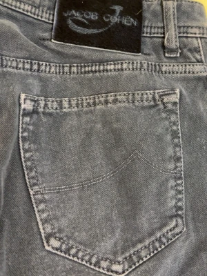 Gråblå jeans från Jacob Cohen - Snygga gråblå jeans från Jacob Cohen med klassisk femficksdesign och raka ben. Jeansen har en diskret tvättad look och patch med logga bak i midjan. Tillverkade i mjukt denimtyg som ger en avslappnad men stilren känsla.