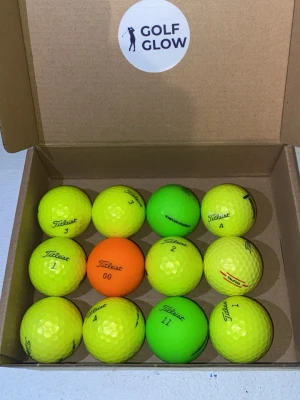 Titleistmix färgade  - Säljer ett set med tolv golfbollar i olika neonfärger, främst gula men även en orange och två gröna. Bollarna ligger i en kartong märkt Golf Glow och flera av dem har Titleist-logga. Perfekt för dig som vill synas på golfbanan.