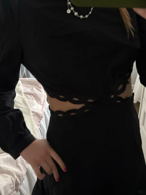 Svart klänning, prislapp kvar! - Svart långärmad topp från Musy Muse med unika utskurna detaljer vid midjan. Tillverkad i mjuk bomull och har en kroppsnära passform som ger en modern och edgy look. Perfekt för dig som gillar statement-plagg.