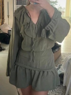 H&M khaki olivgrön volangklänning - Olivgrön slutsåld klänning från H&M i storlek M. Lappen är avklippt, och jag har aldrig använt den pga för stor. Köpt på vinted och mycket fint skick!! (Bilden är från förra säljaren)