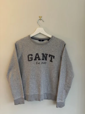 GANT Tröja  - Klassisk grå sweatshirt från GANT med rund halsringning och tryckt logga. Passar från 155/165 cm. Har inga defekter. Perfekt nu till våren!