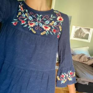 Marinblå volangklänning från zara - Marinblå klänning ifrån Zara med volanger och ärm, så fina blommor på också!! Köpt på barnavdelningen men passar en Xxs!