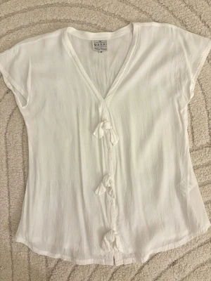 Vit kortärmad topp blus t-shirt rosetter rosett bow ribbon cute coquette unique rare vintage retro - Vit kortärmad topp med V-ringning fram. Väldigt unik och har fina söta rosetter fram.  • Från märket ”The Masai Clothing Company” • Storlek M