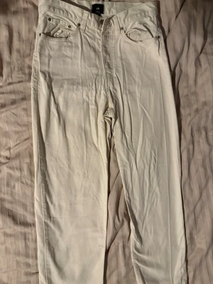 Vita raka jeans från H&M - Säljer ett par vita jeans från H&M med rak passform och klassisk femficksdesign. Jeansen har normal midja och är tillverkade i ett mjukt bomullsmaterial. Perfekta för dig som vill ha en clean och stilren look.