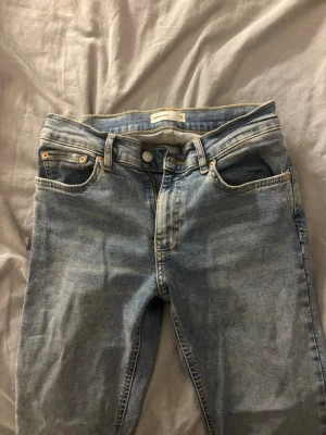 Ljusblå bootcut jeans från Weekday - Säljer ett par ljusblå bootcut jeans från Gina tricot med klassisk femficksmodell och dragkedja. Jeansen har en snygg tvättad look och raka ben som går ut lite nedtill. Perfekta för en avslappnad och trendig stil.