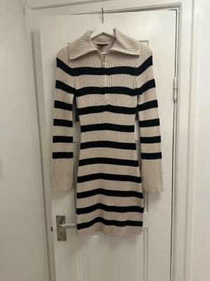 Randig klänning - Stickad, randig klänning med krage. Använd 1 gång så säljes i toppskick. Stretchig i materialet. 