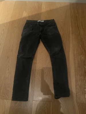 Svarta slim fit jeans Levis 512 - Säljer ett par svarta slim fit jeans med klassisk femficksdesign och normal midja. Jeansen har smala ben och är tillverkade i ett mjukt bomullsmaterial med lite stretch för extra komfort. Perfekta för en clean och stilren look.