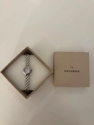 Mockberg silverfärgad armbandsklocka - Stilren armbandsklocka från Mockberg i silverfärg med klassisk rund urtavla och länkarmband i metall. Kommer i original ask. Endast använd en gång, superfint skick. Kommer dessutom med extra länkar som man enkelt kan knäppa fast själv för att justera storleken på klockan!😊Orginalpris: 1799 