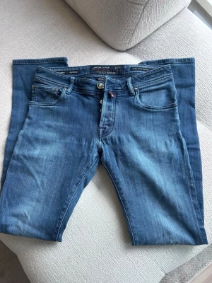 Jacob Cohen Jeans - PRESENTERAR: Ett par blå Jacob Cohen jeans i storlek W30. Bra skick inga hål eller liknande. Slitningar på baksidan av jeansen tror fabriksgjorda, oavsett ger det jeansen mer liv. Väldigt schyssta jeans. Pris: 399 kr (nog ej prutbart) 