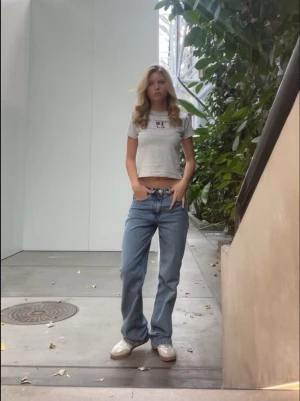 Blå raka jeans med spetsdetaljer - Säljer ett par blå raka jeans med unika spetsdetaljer på bakfickorna. Jeansen har en avslappnad passform och normal midja. Materialet är klassisk denim och spetsen på fickorna ger en cool och personlig touch.