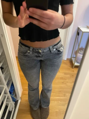 True religion grå JOEY low rise flare jeans  - Säljer mina  true religion jeans då de är  något korta på mig som är 173. De har en fin relativt mörkgrå tvätt med lila sömmar. Jeansen är även i nytt skick och kommer inte med några defekter. Jeansen är originellt köpta från Nelly