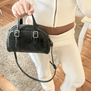 Svart axelväska i skinn - Snygg svart axelväska i skinn med dragkedja och justerbar axelrem. Perfekt för att bära med sig det viktigaste med stil. Återsäljer så är inte mina bilder🤗